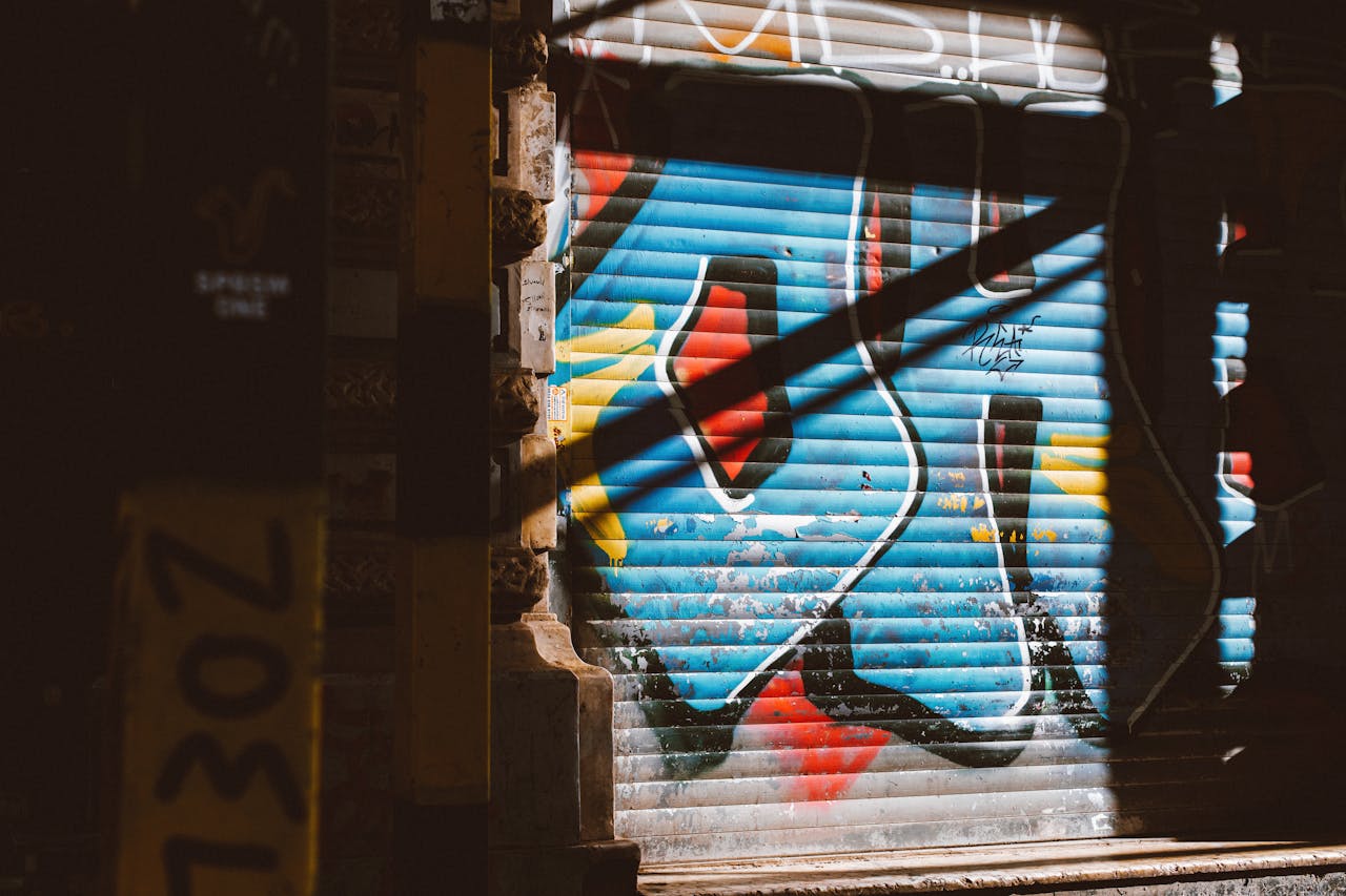 Vibrant urban graffiti art on a garage door under sunlight and shadow.